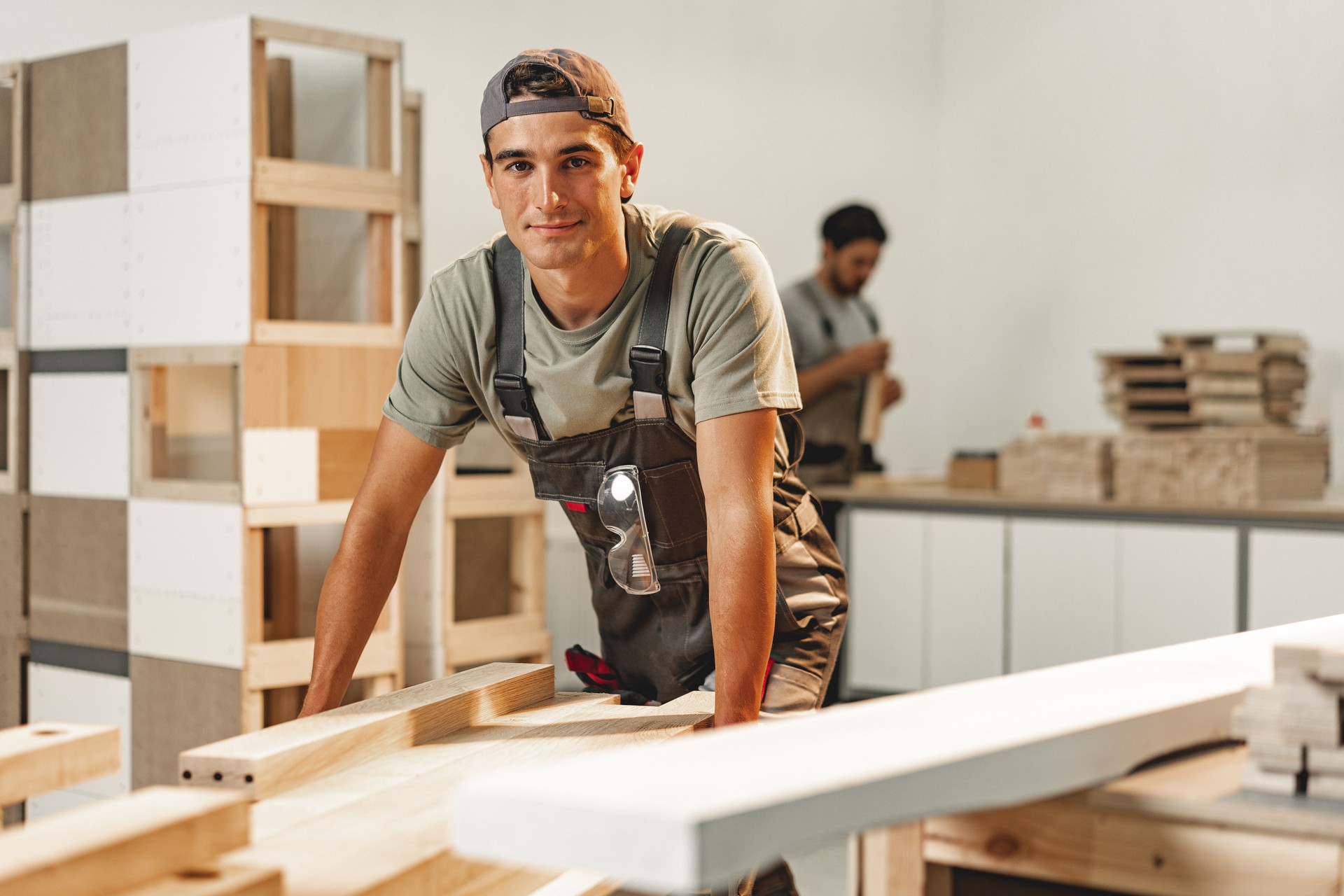 Porträt eines jungen männlichen Tischlers, der in der Holzwerkstatt steht