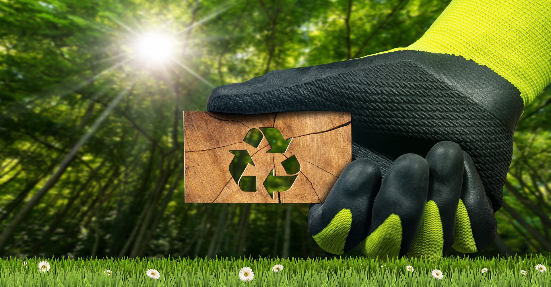 Behandschuhte Hand hält ein Stück Holz mit einem Recycling-Symbol